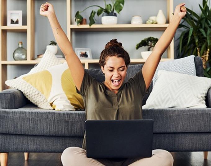 Woman sitting in front of laptop with both arms up - Level Pay Program Banner