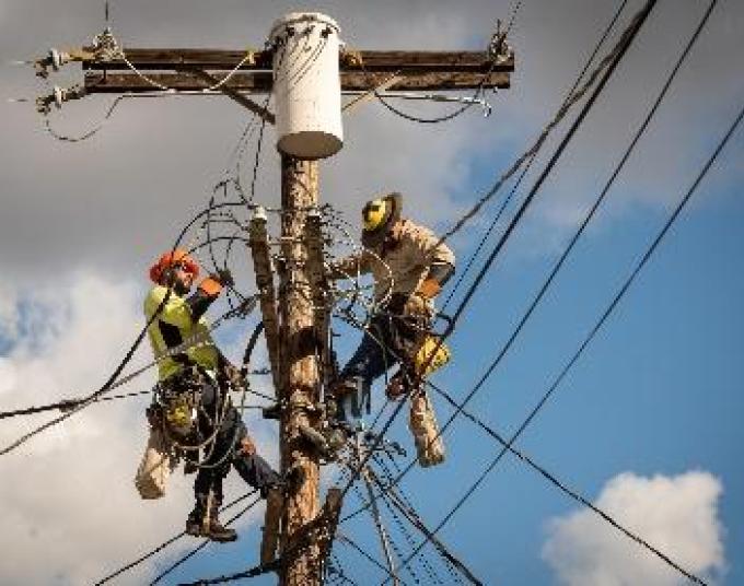 Electrical workers on a utility pole fixing electrical wires.