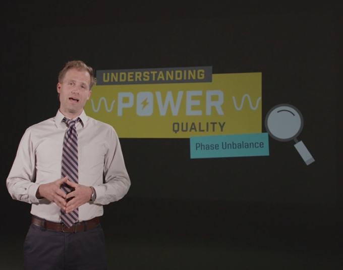 Business man stands in front of a graphic that says: Understanding Power Quality – Phase Unbalance