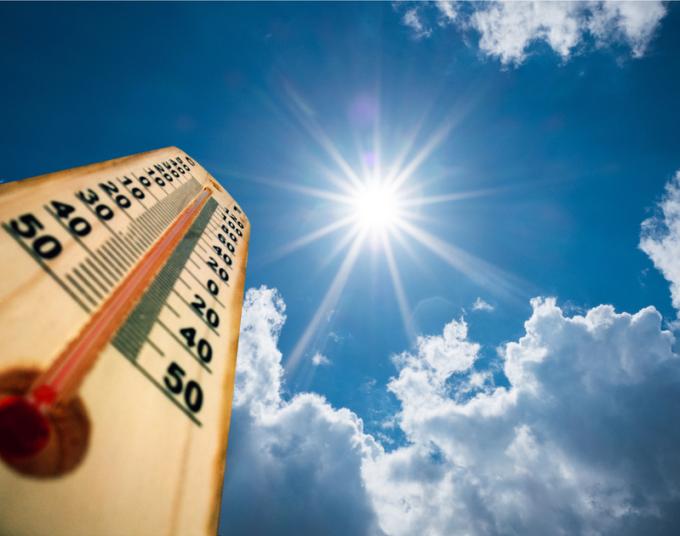 A thermometer is shown against a blue, sunny sky.