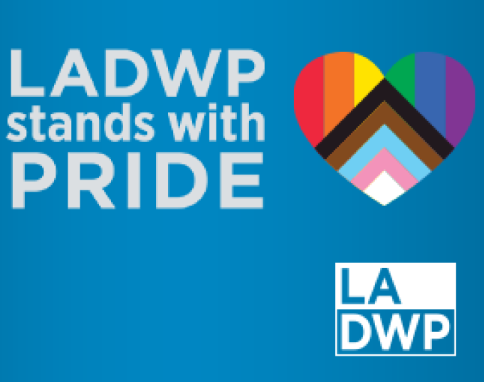 Blue background with white text that says, “LADWP Stands with PRIDE.” Next to the text is a heart with rainbow stripes on the top half and white, light blue, light pink, brown and black stripes in the shape of a diamond on the bottom half. The LADWP logo is in the right hand corner in white.