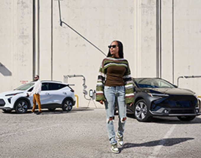 Two people standing outside by two electric vehicles.