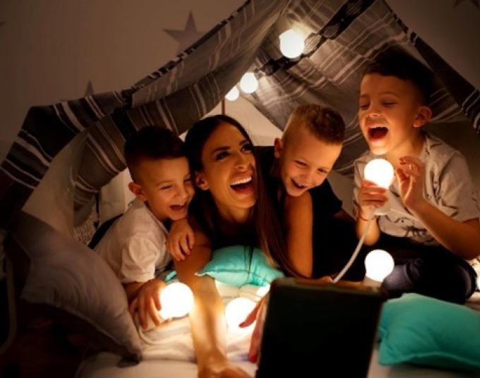 Smiling woman and smiling children with string lights.