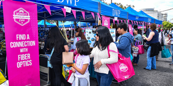 Attendees visiting career booths at LADWP’s Women’s Career & Wellness Expo. A banner reads, “Find a Connection with Fiber Optics.” 