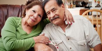 La pareja sonriente está sentada. La mujer tiene su brazo alrededor del hombre.